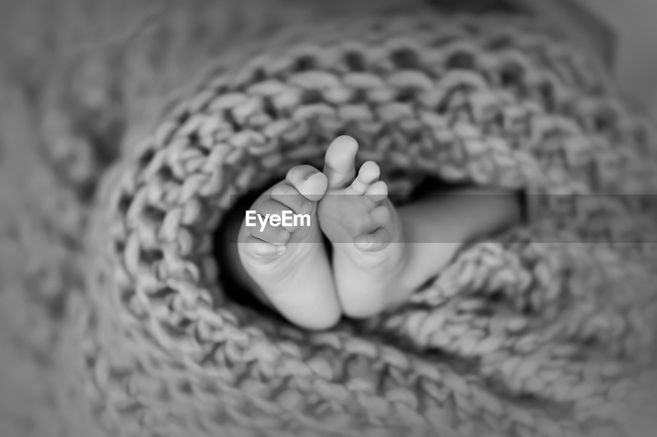 Newborn baby feet wrapped in knitted blanket in black and white