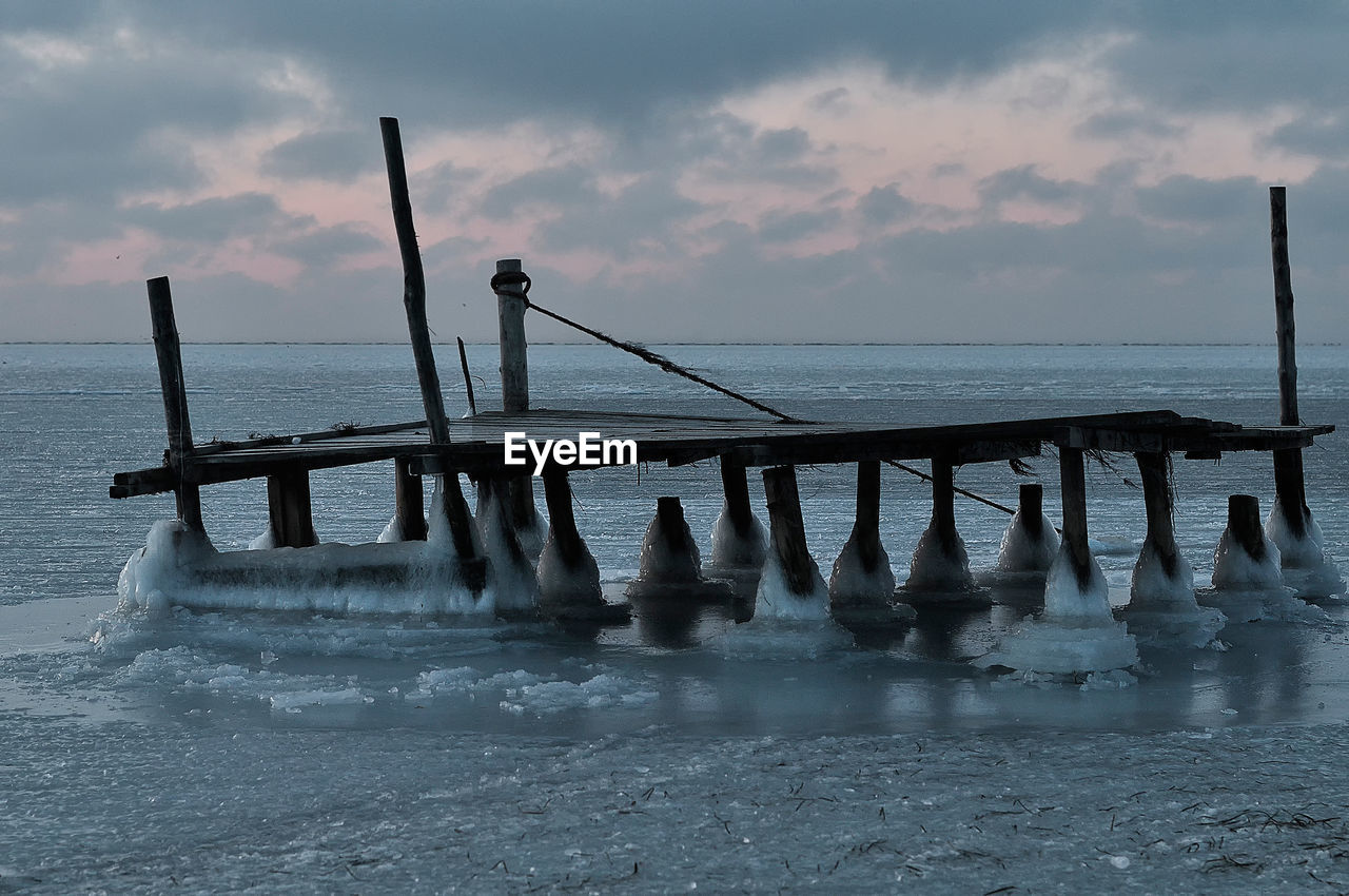 Pier over sea against sky during sunset