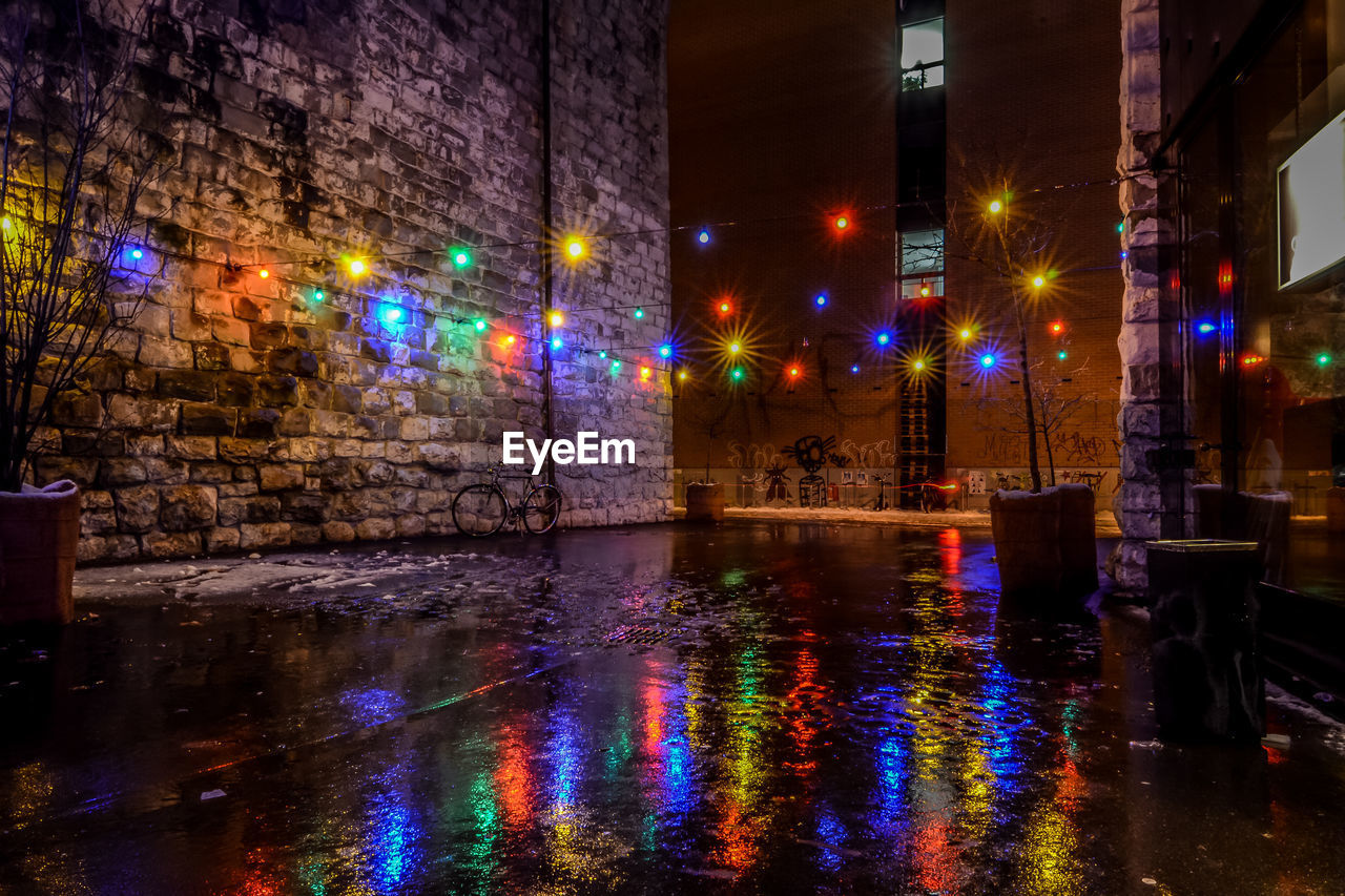 REFLECTION OF ILLUMINATED BUILDINGS ON WET STREET