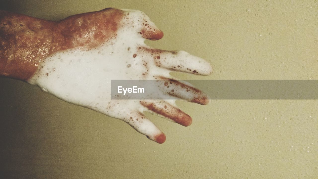 CLOSE-UP OF HUMAN HAND AGAINST GRAY BACKGROUND