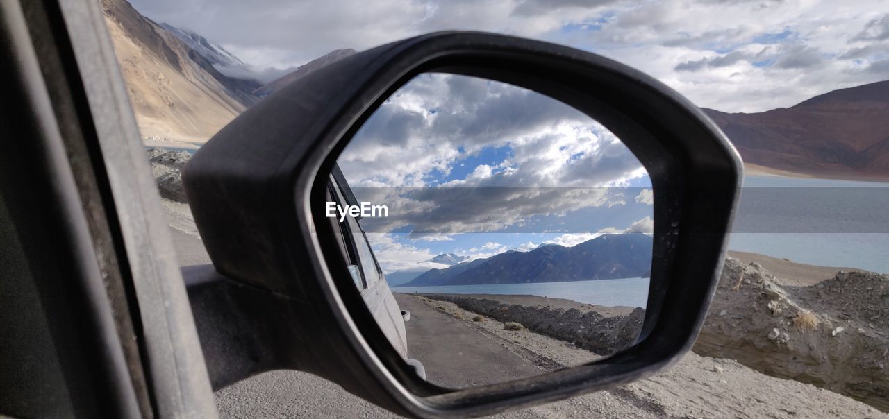 Reflection of mountains seen through car side-view mirror