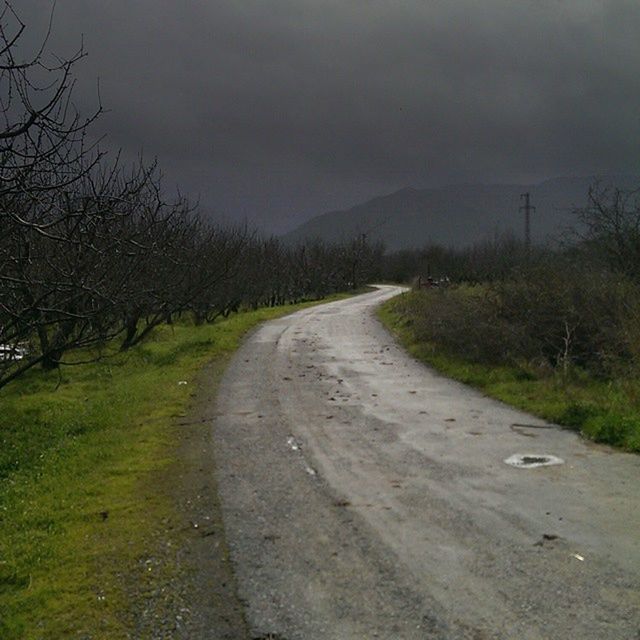 ROAD PASSING THROUGH FIELD AGAINST CLOUDY SKY