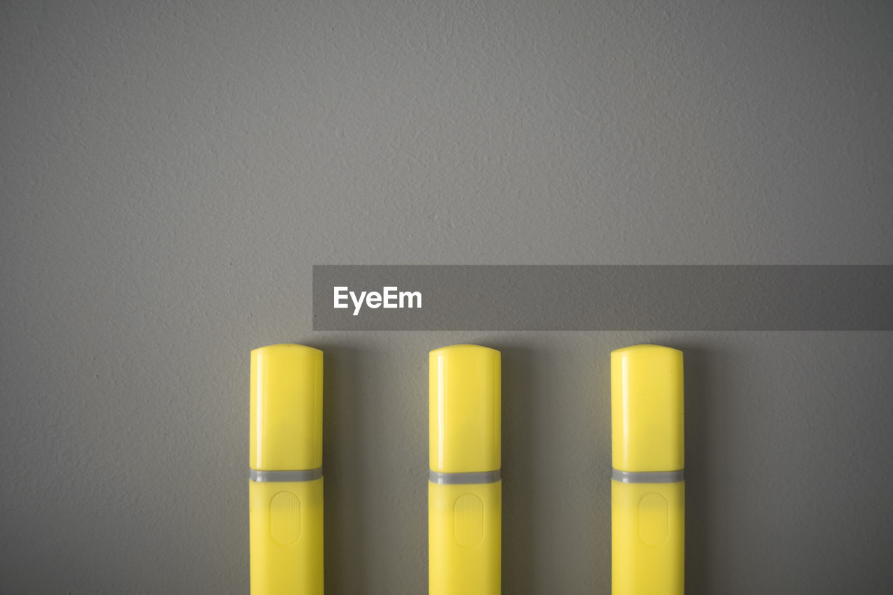 yellow, cylinder, indoors, no people, gray, wall - building feature, gray background, close-up, lighting, copy space, studio shot, in a row, side by side