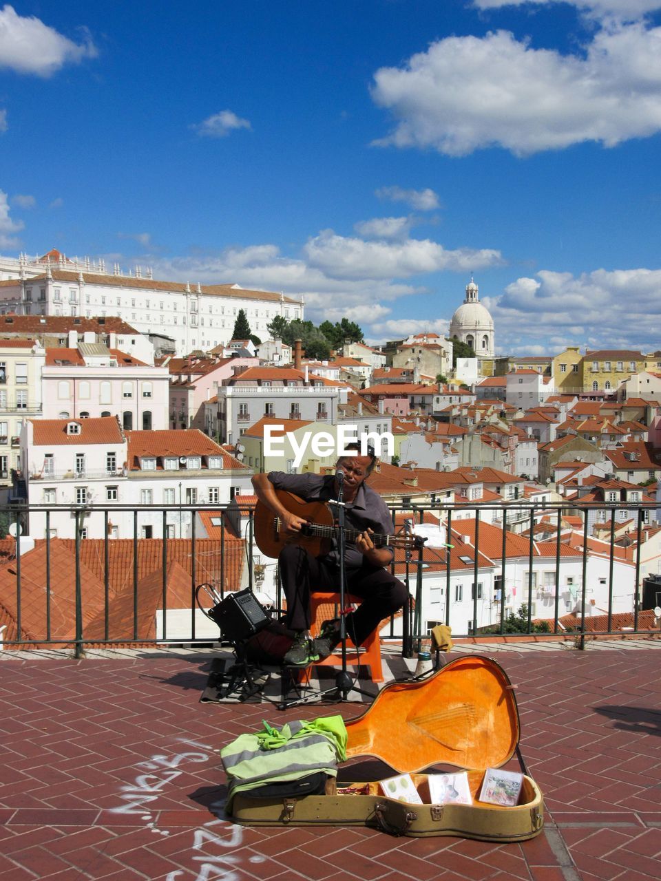 MAN SITTING AT TOWN AGAINST SKY