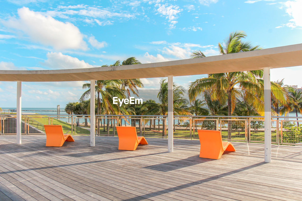 Three orange lounge chairs on a wooden deck at south pointe park, miami beach, fl, usa.