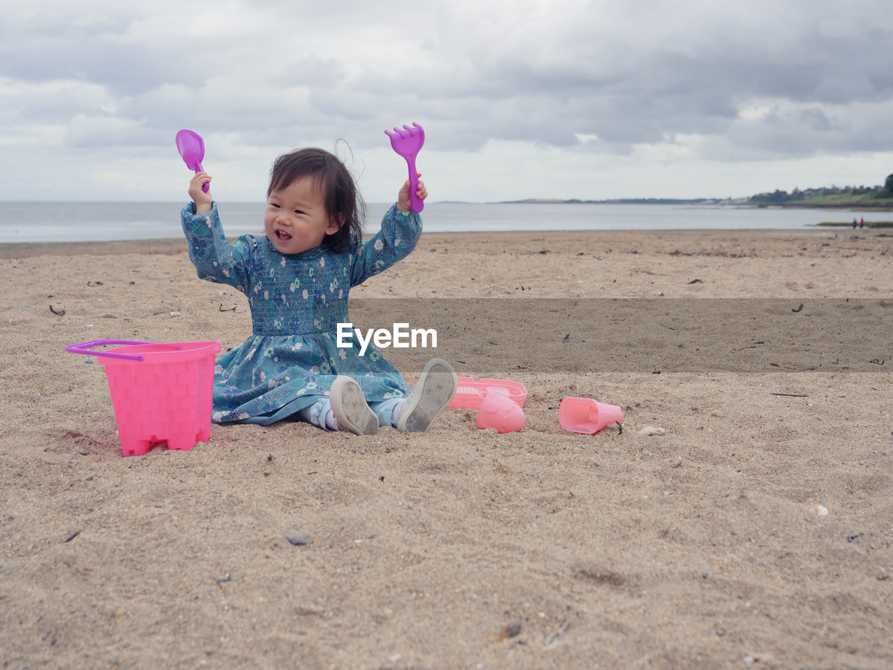 Full length of girl playing toys while sitting on sand at beach