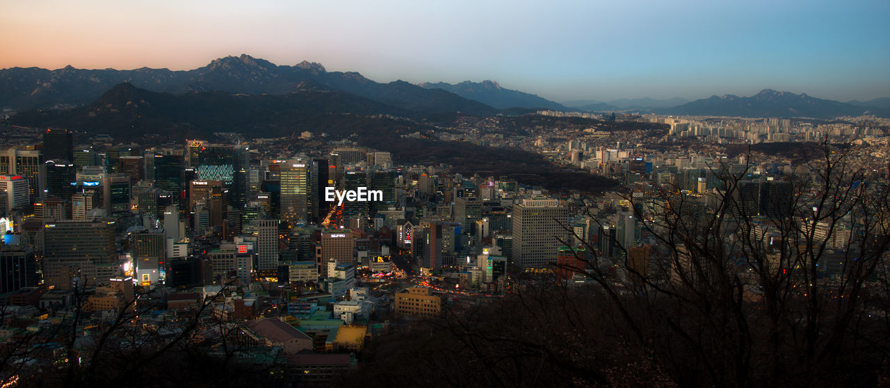 HIGH ANGLE VIEW OF ILLUMINATED BUILDINGS AGAINST SKY