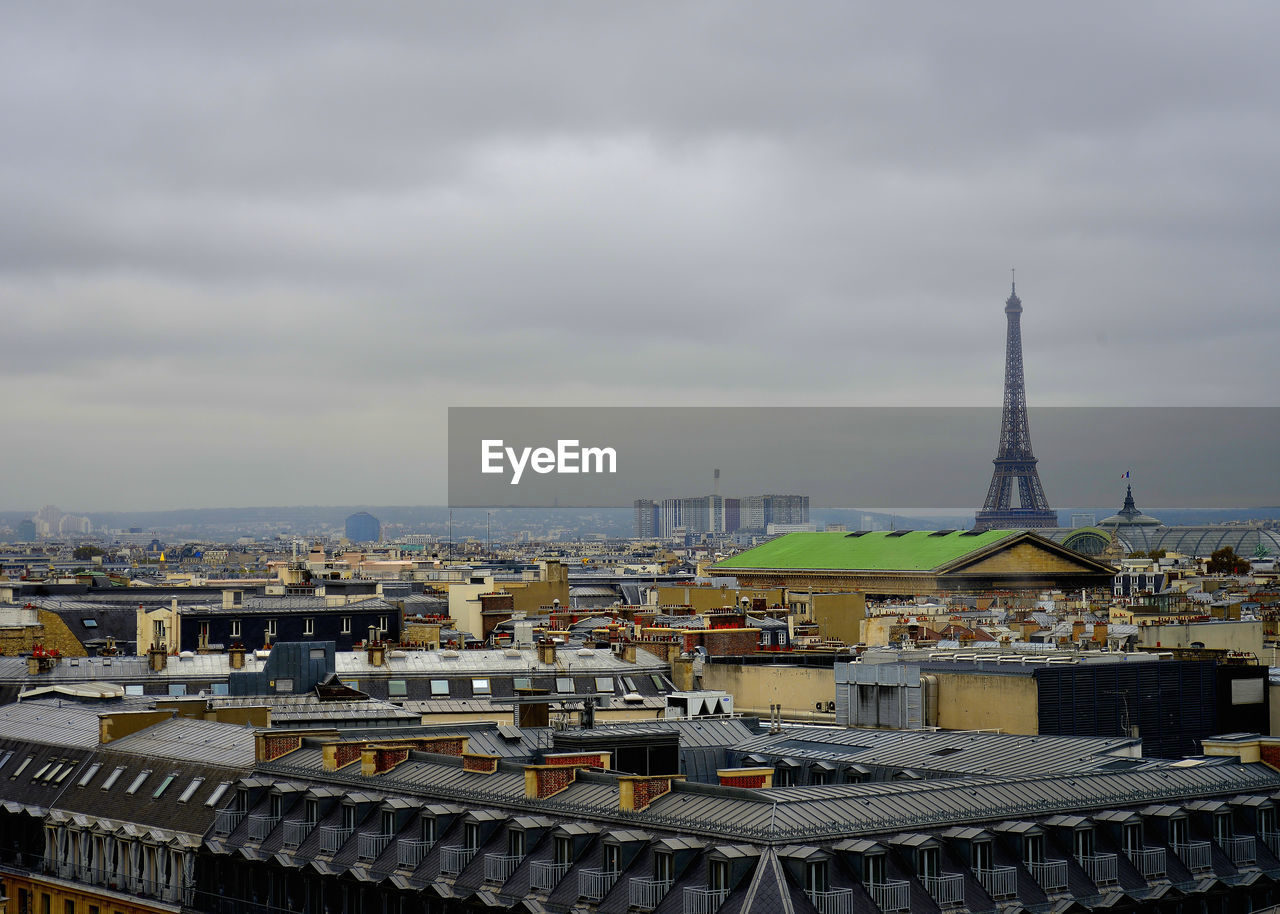 Aerial view of buildings in city against cloudy sky