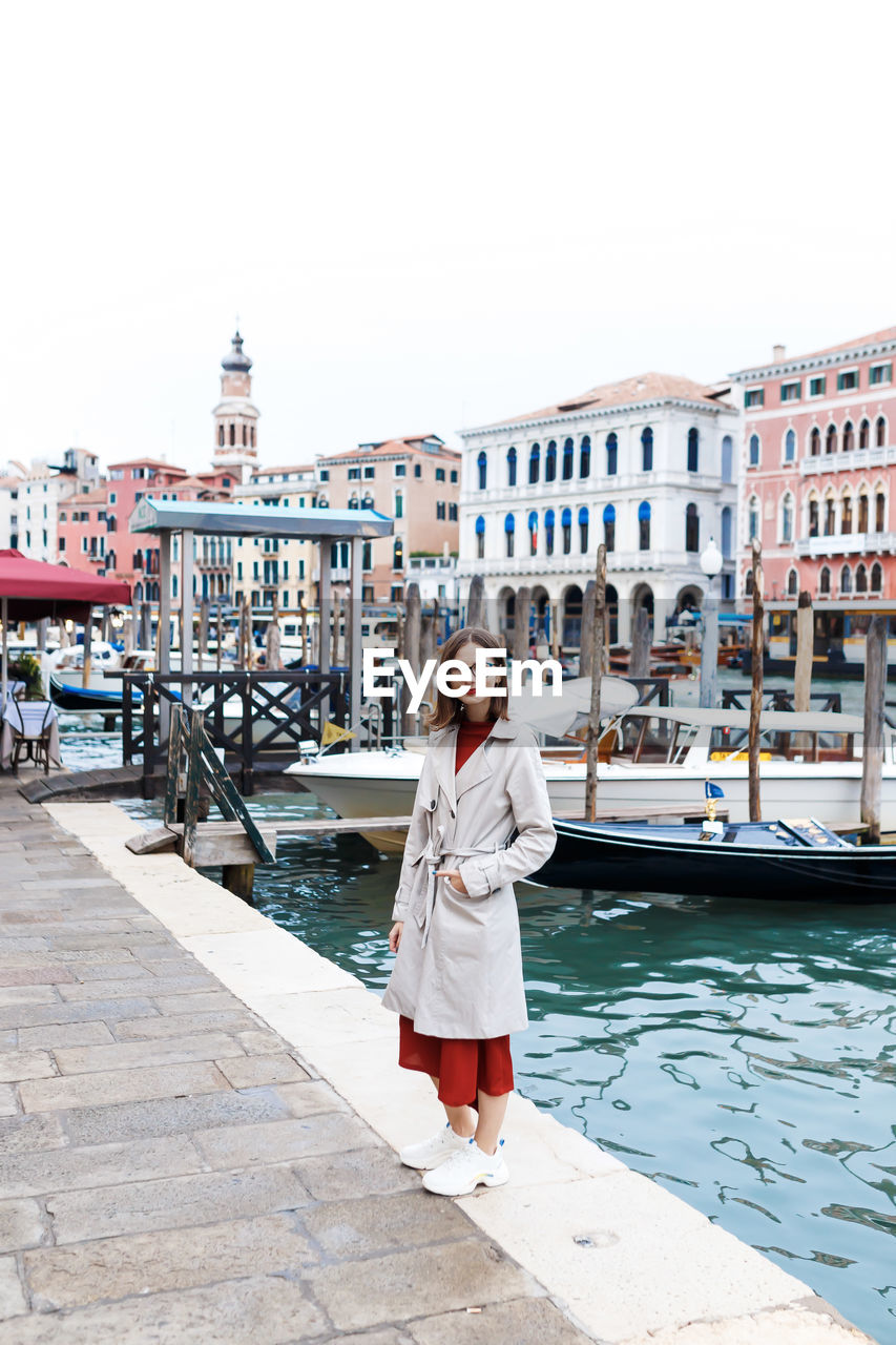 Young tourist in dress and coat on the streets of venice