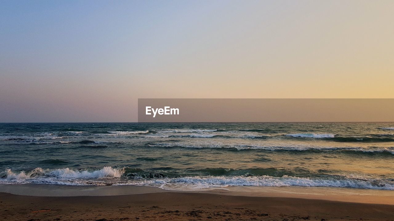 SCENIC VIEW OF BEACH AGAINST SKY DURING SUNSET