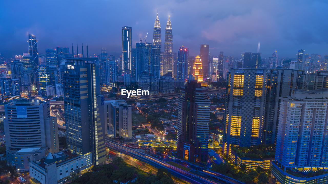 Illuminated buildings in city against sky