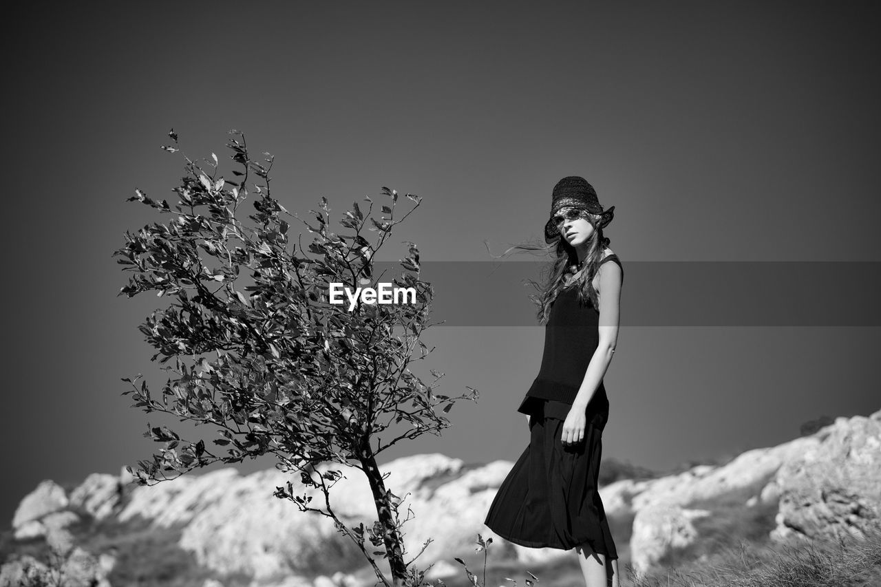 Portrait of young woman standing against sky