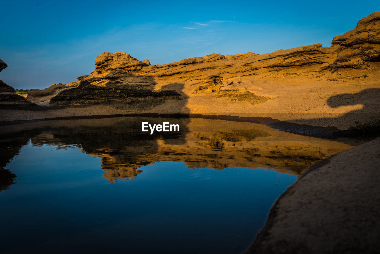 Reflection of mountain range in lake against blue sky