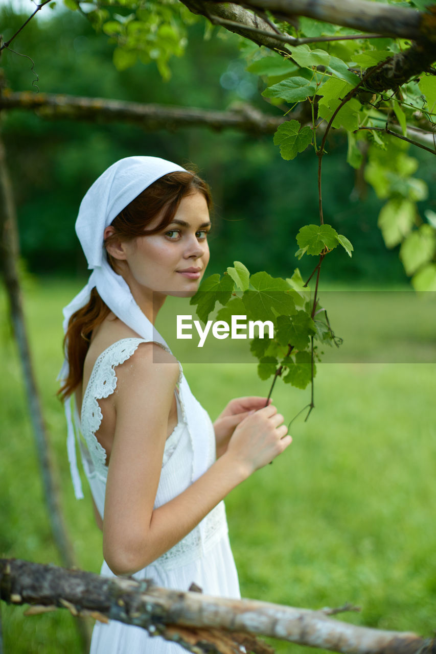 portrait of smiling young woman standing by plants