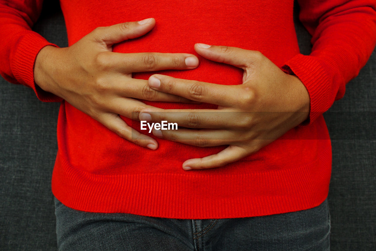 CLOSE-UP OF COUPLE HOLDING HANDS TOUCHING RED