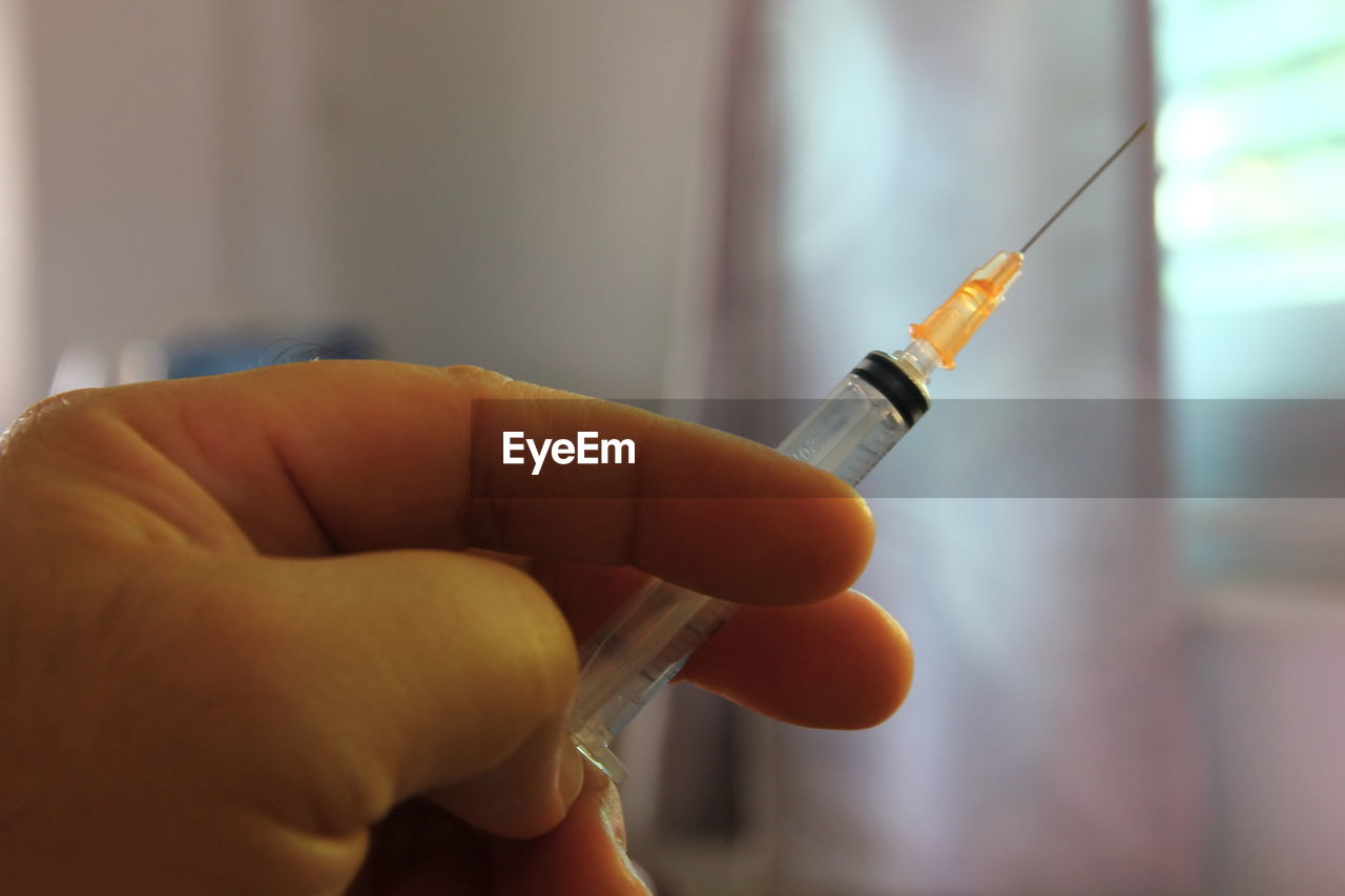 Close-up of hand holding syringe