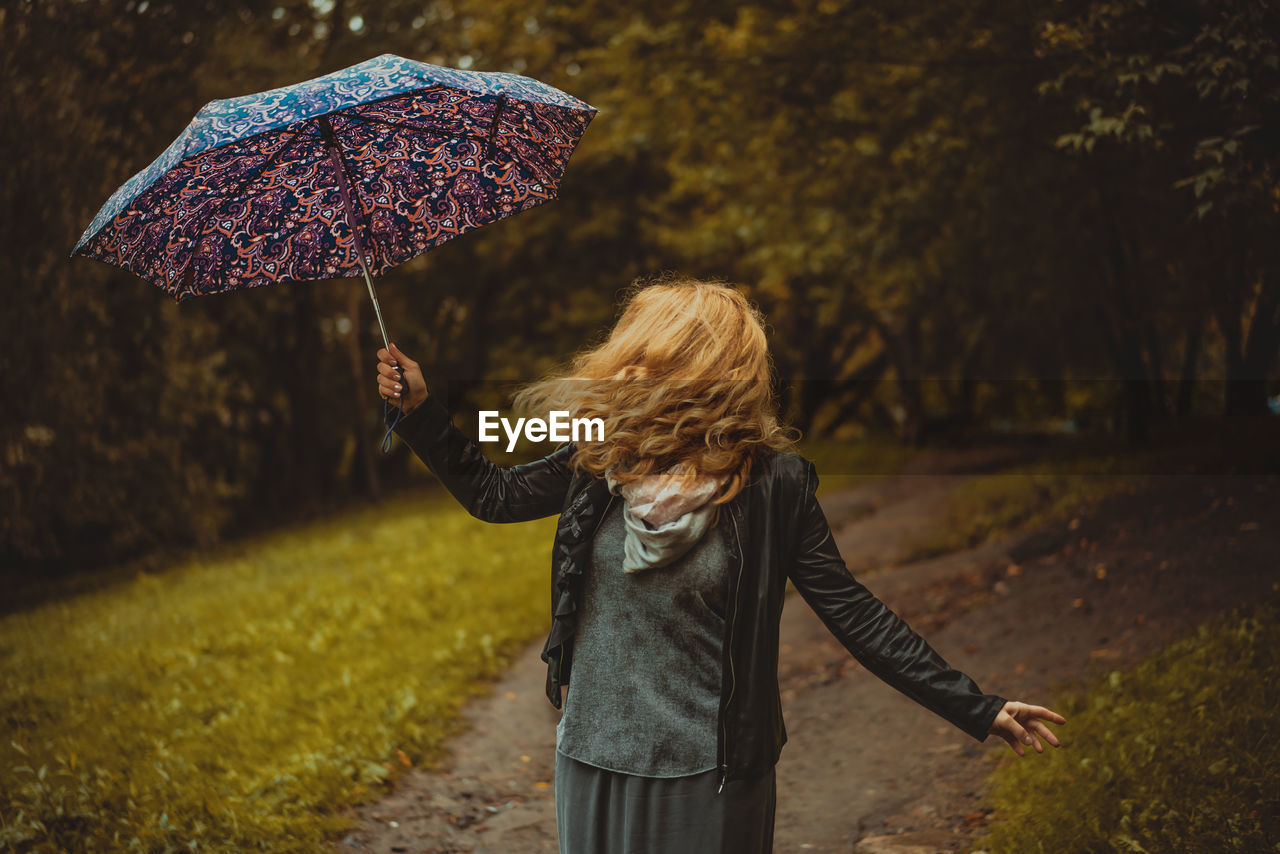 Woman with umbrella on footpath