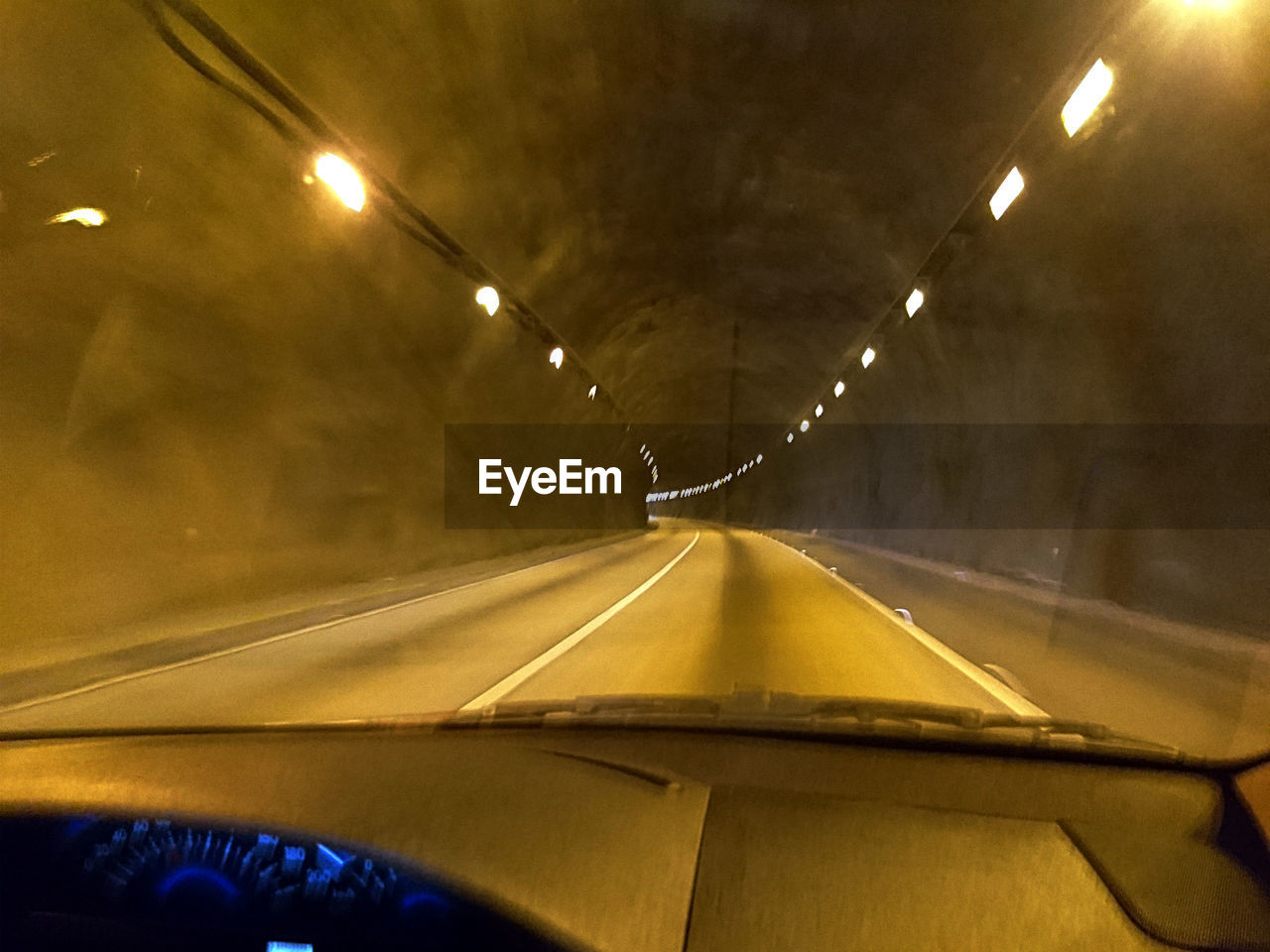 CROPPED IMAGE OF CAR ON ROAD IN ILLUMINATED TUNNEL