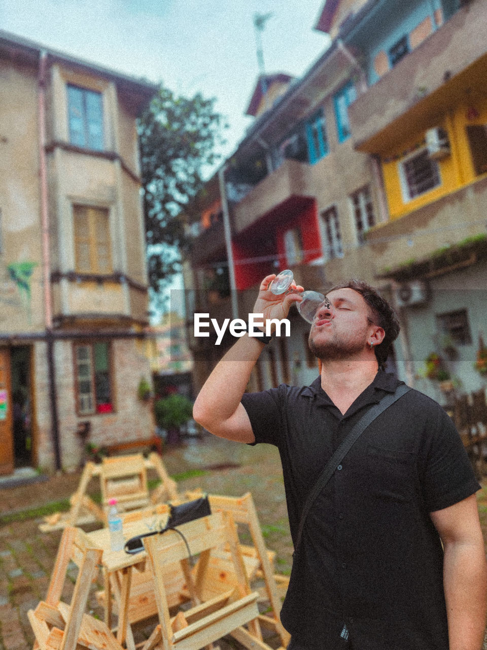 portrait of young man standing against built structures