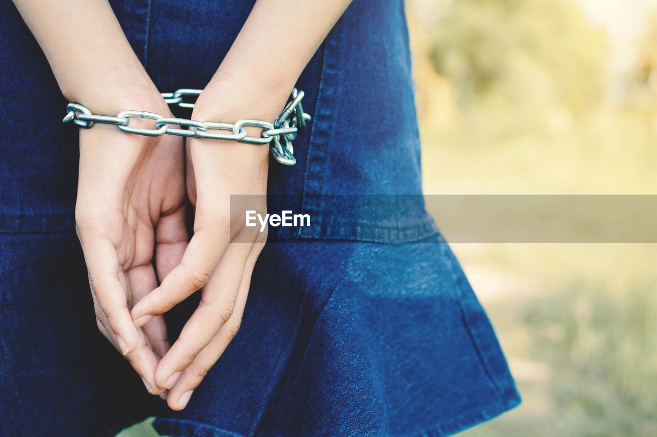 Midsection of woman hands tied with chain