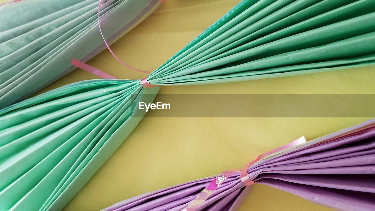 HIGH ANGLE VIEW OF MULTI COLORED PAPER TIED UP ON SHELF