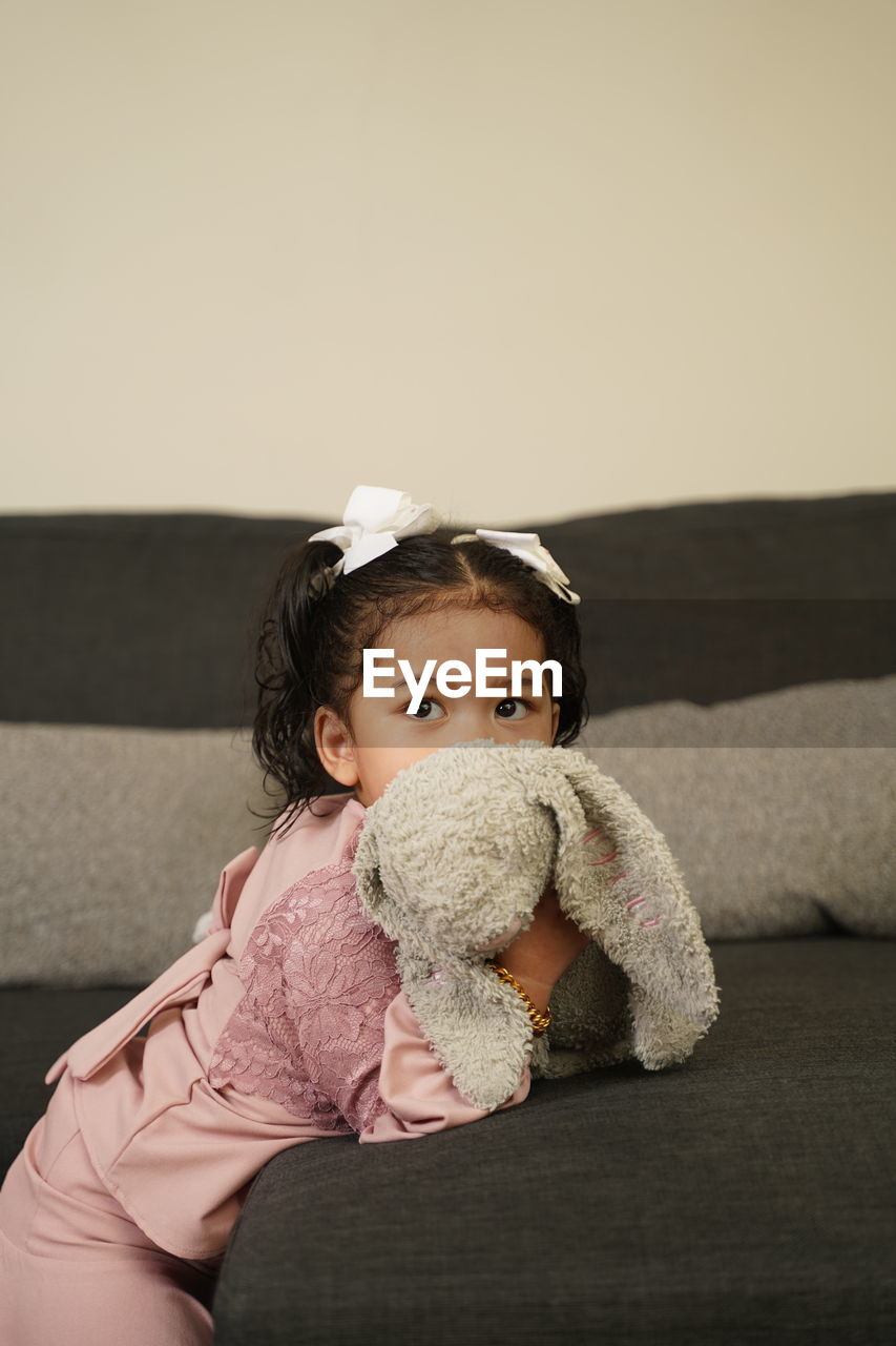 Portrait of cute baby girl sitting on sofa at home