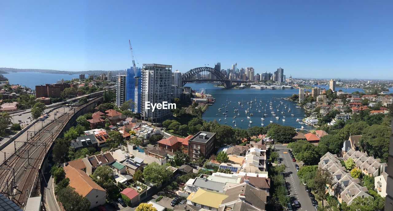 HIGH ANGLE VIEW OF CITY BY SEA AGAINST SKY