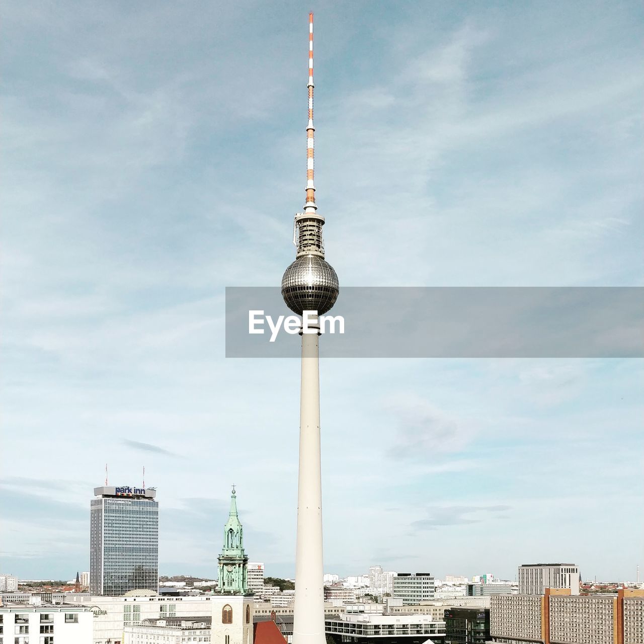 Communications tower in city against sky