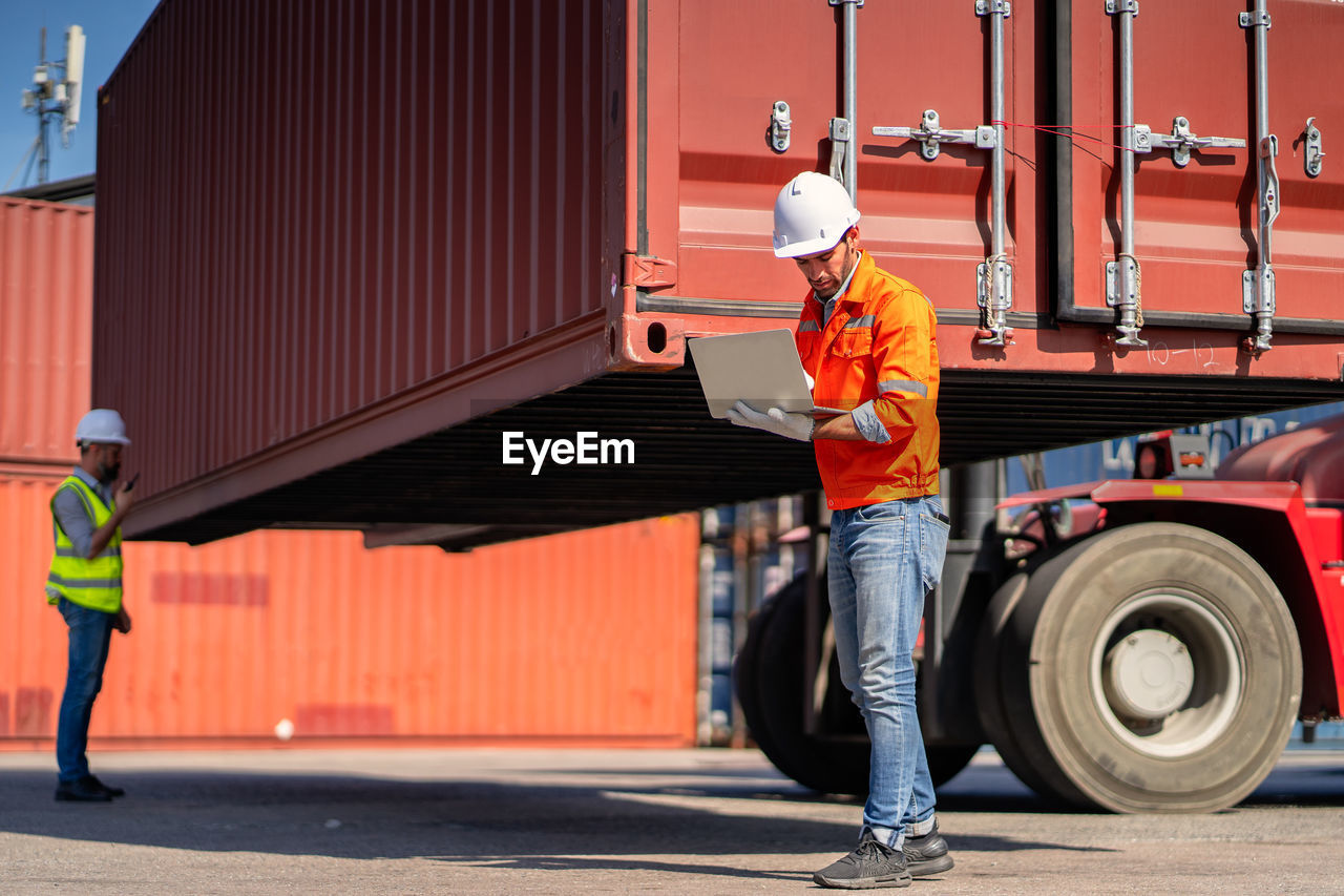 Engineers are overseeing the transportation of cargo with containers inside the warehouse. 