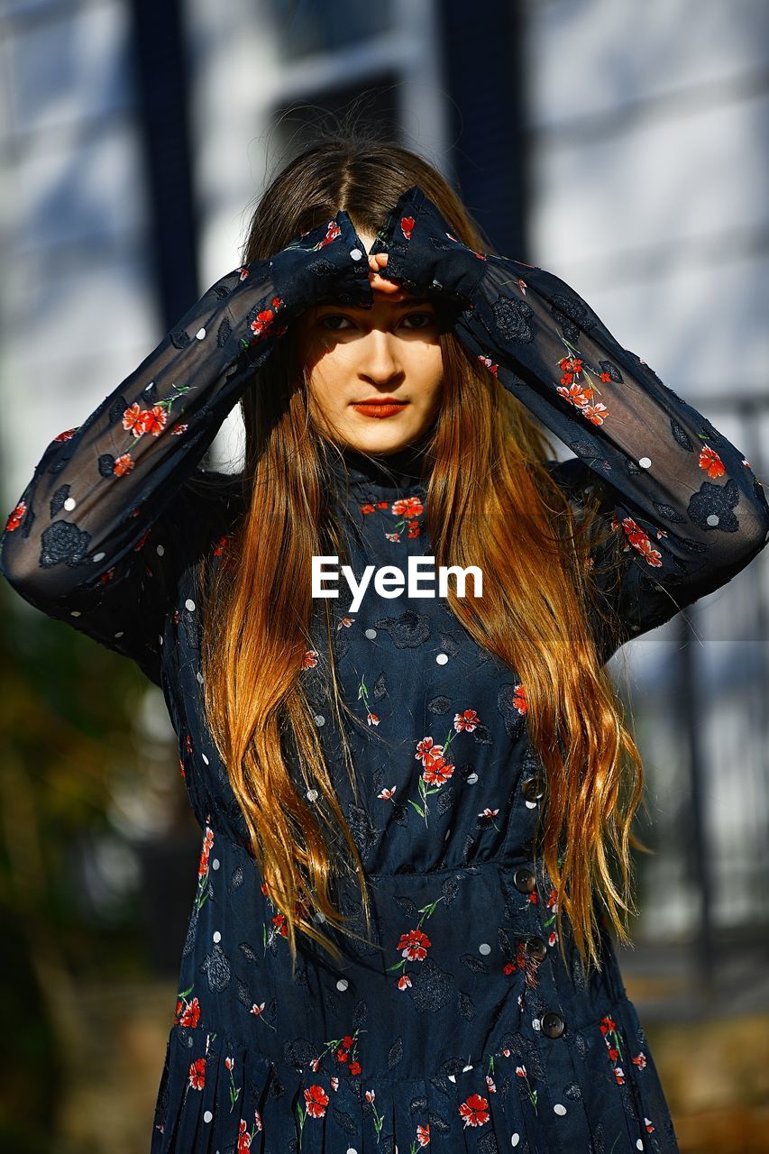 Portrait of young woman shielding eyes on sunny day