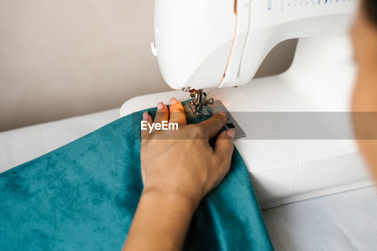 Hands in the process of sewing. women's hands sew fabric on a hobby typewriter at home.