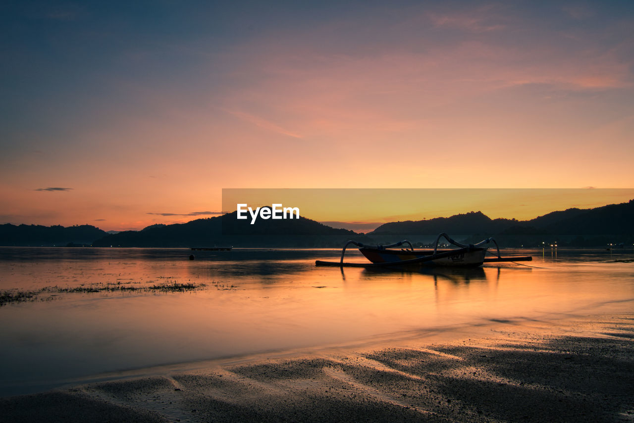 SCENIC VIEW OF LAKE BY SILHOUETTE MOUNTAINS AGAINST SKY DURING SUNSET