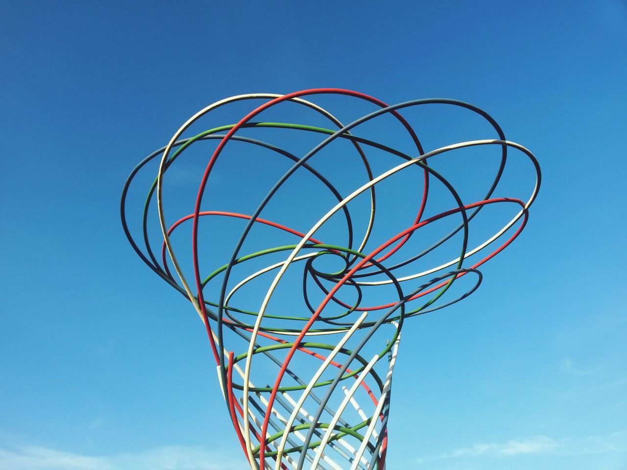 Low angle view of vortex shaped metal structure against blue sky