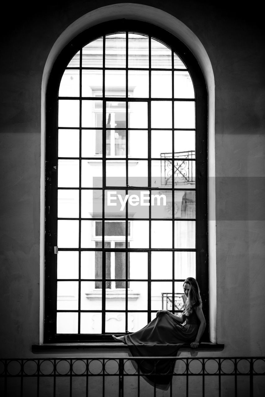 Woman sitting on window sill