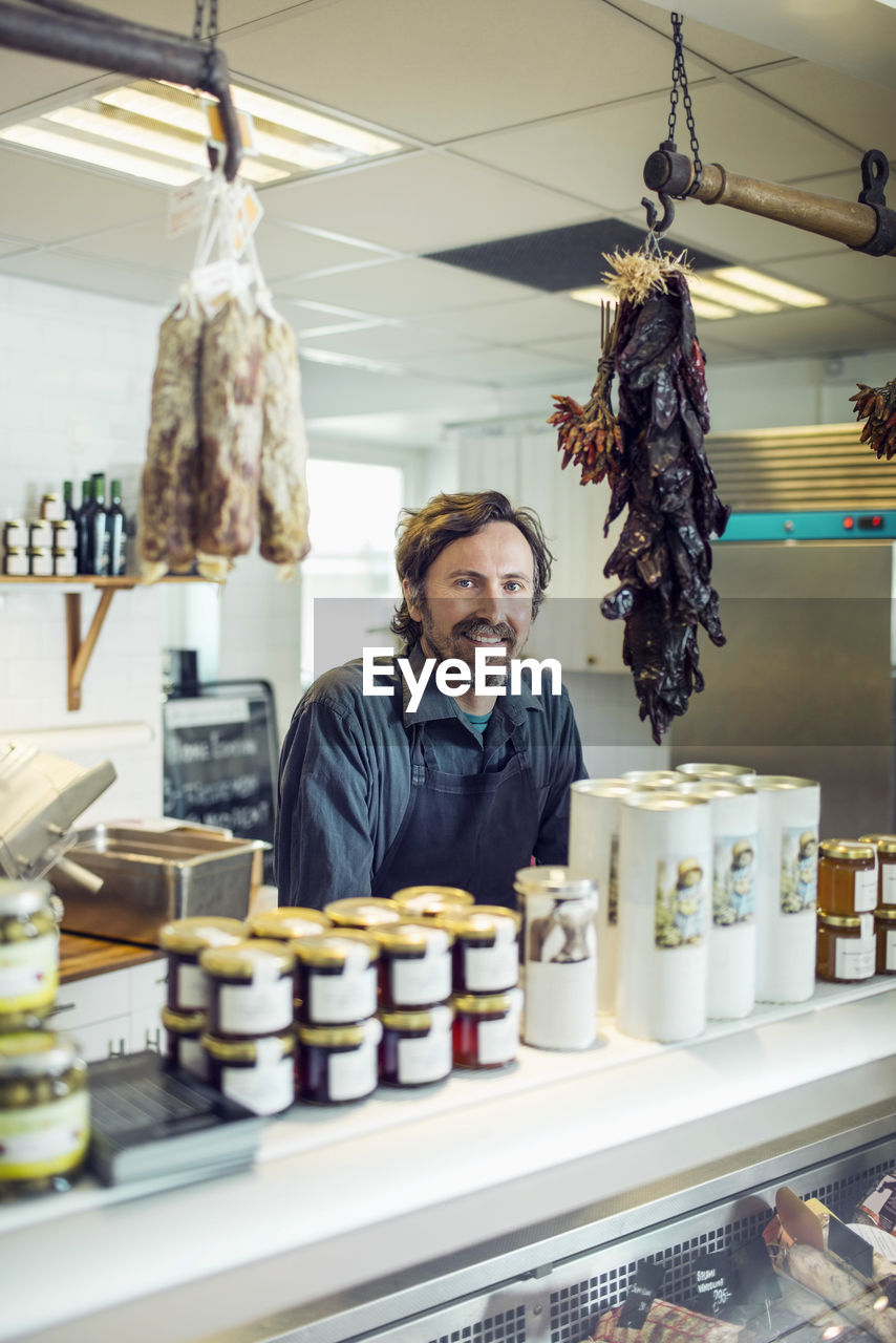 Portrait of confident mature salesman at supermarket counter