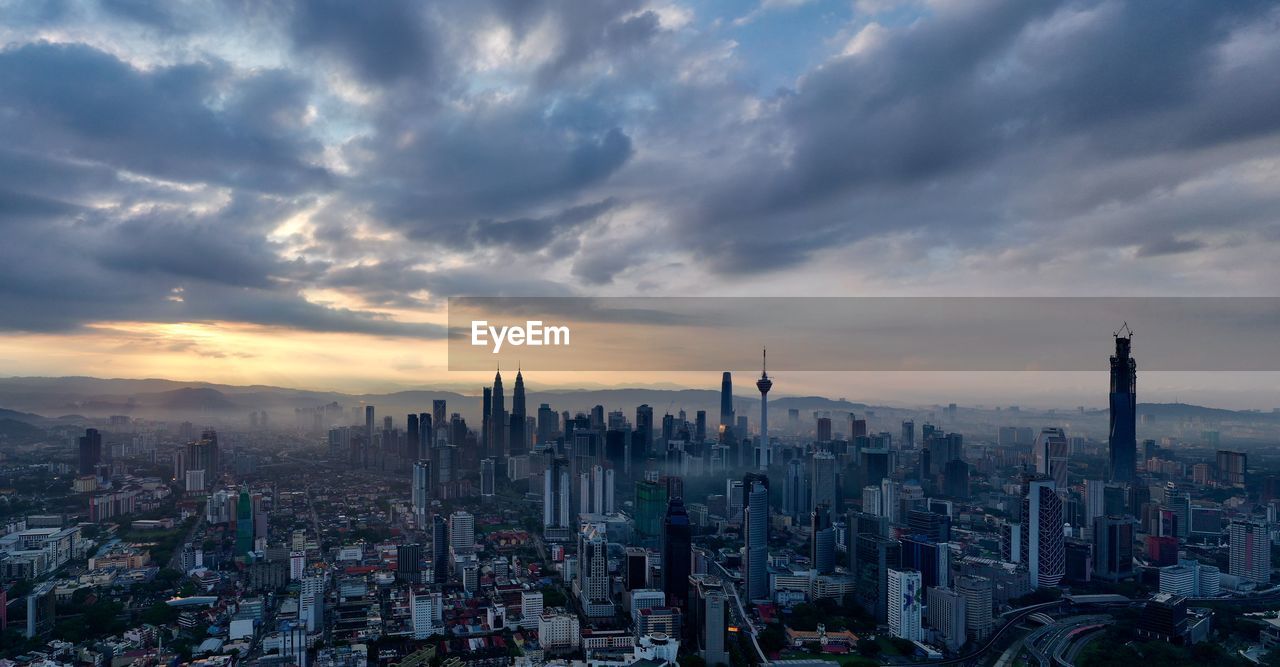 Aerial view of modern buildings in city against sky during sunset