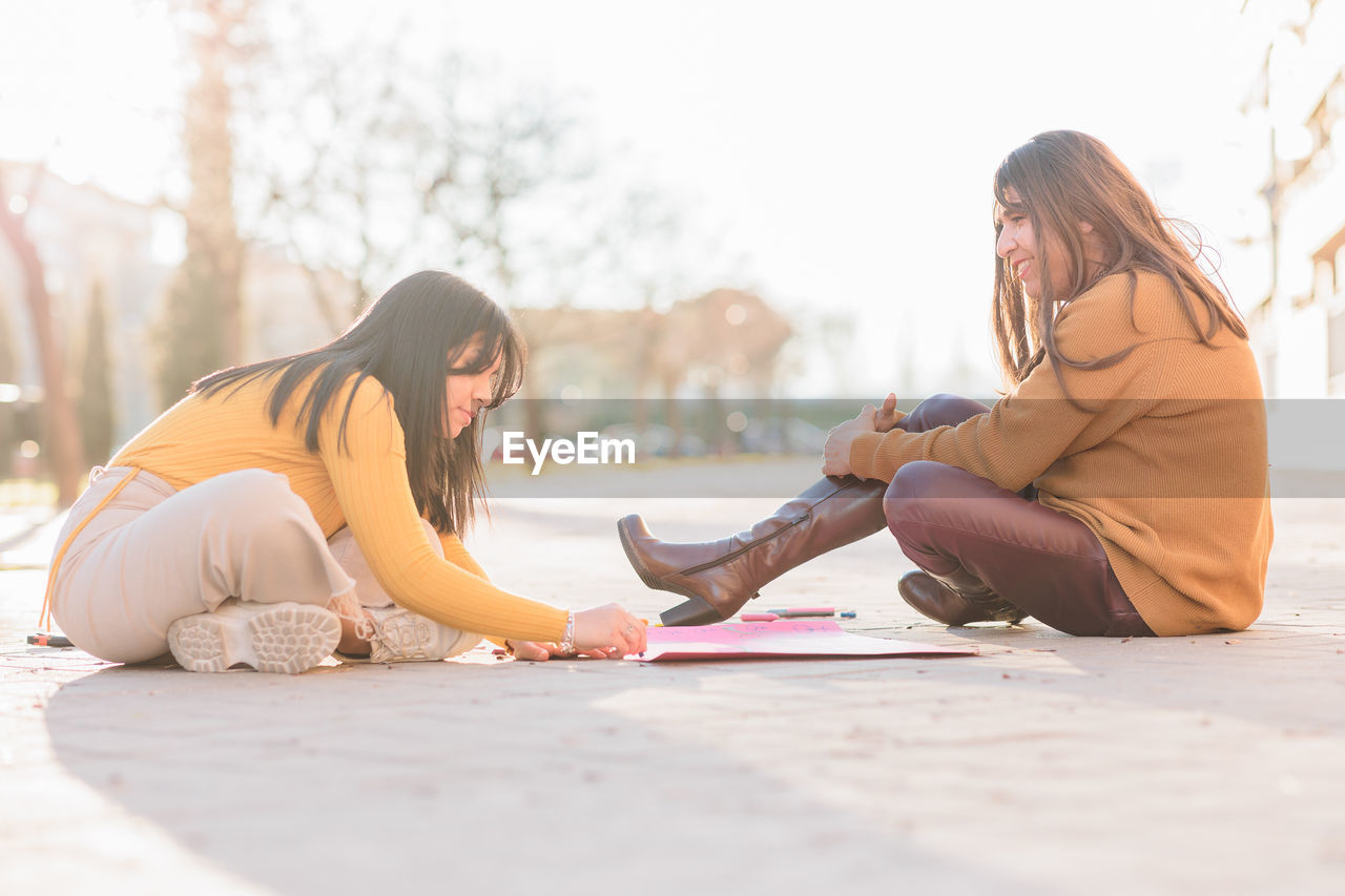 Females writing on posters sitting on street