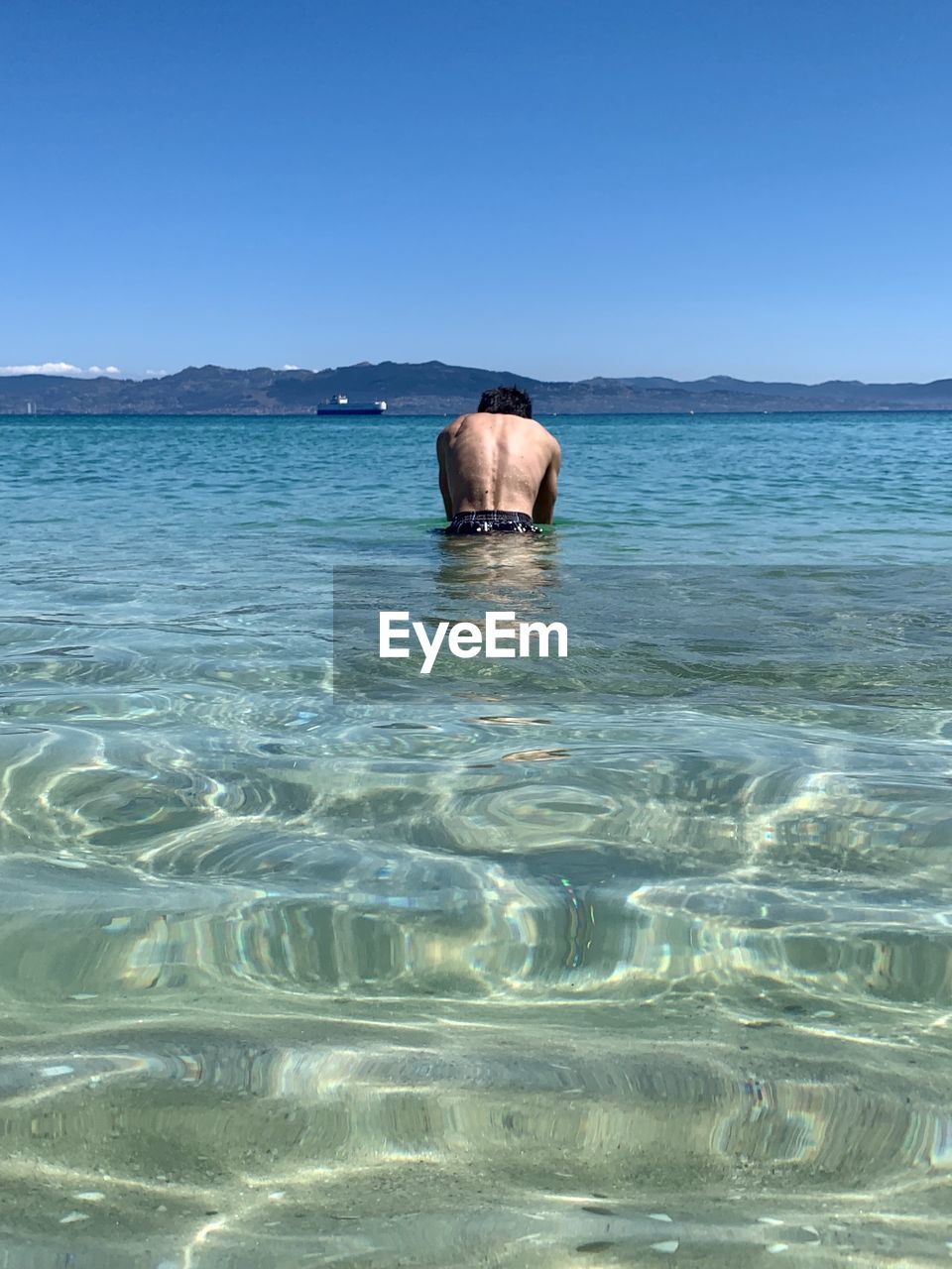 Rear view of shirtless man in sea