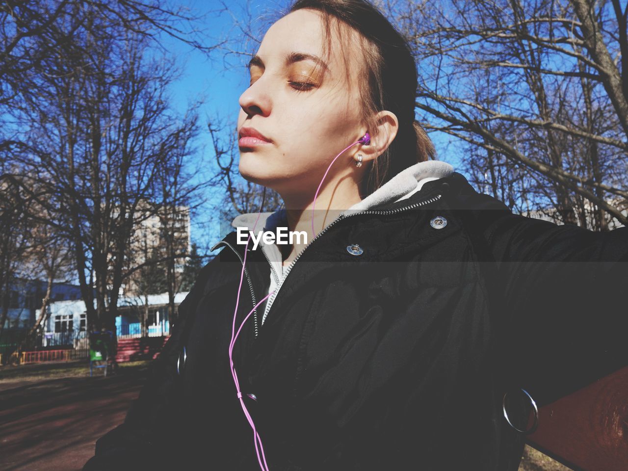 PORTRAIT OF YOUNG WOMAN LOOKING AWAY ON BARE TREE