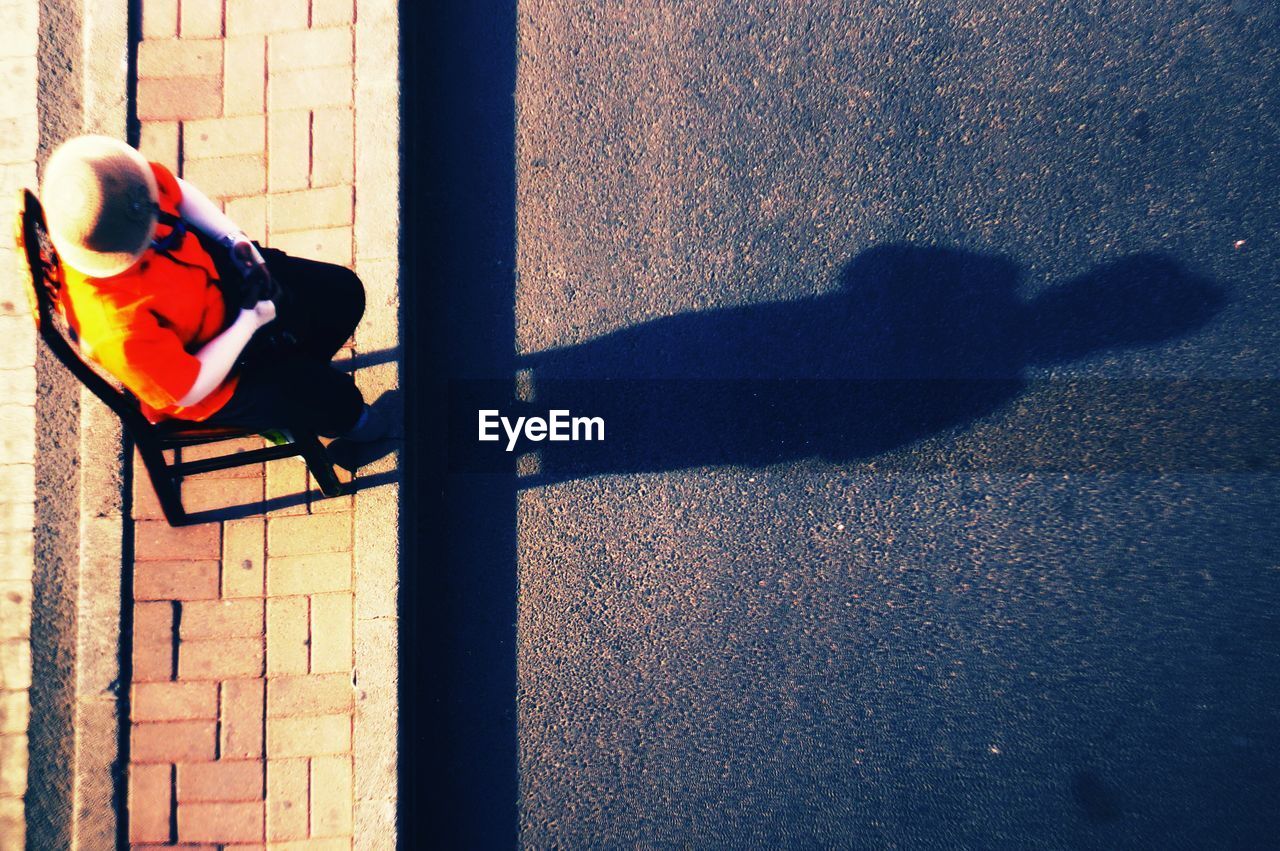 HIGH ANGLE VIEW OF MAN PLAYING WITH SHADOW ON FLOOR