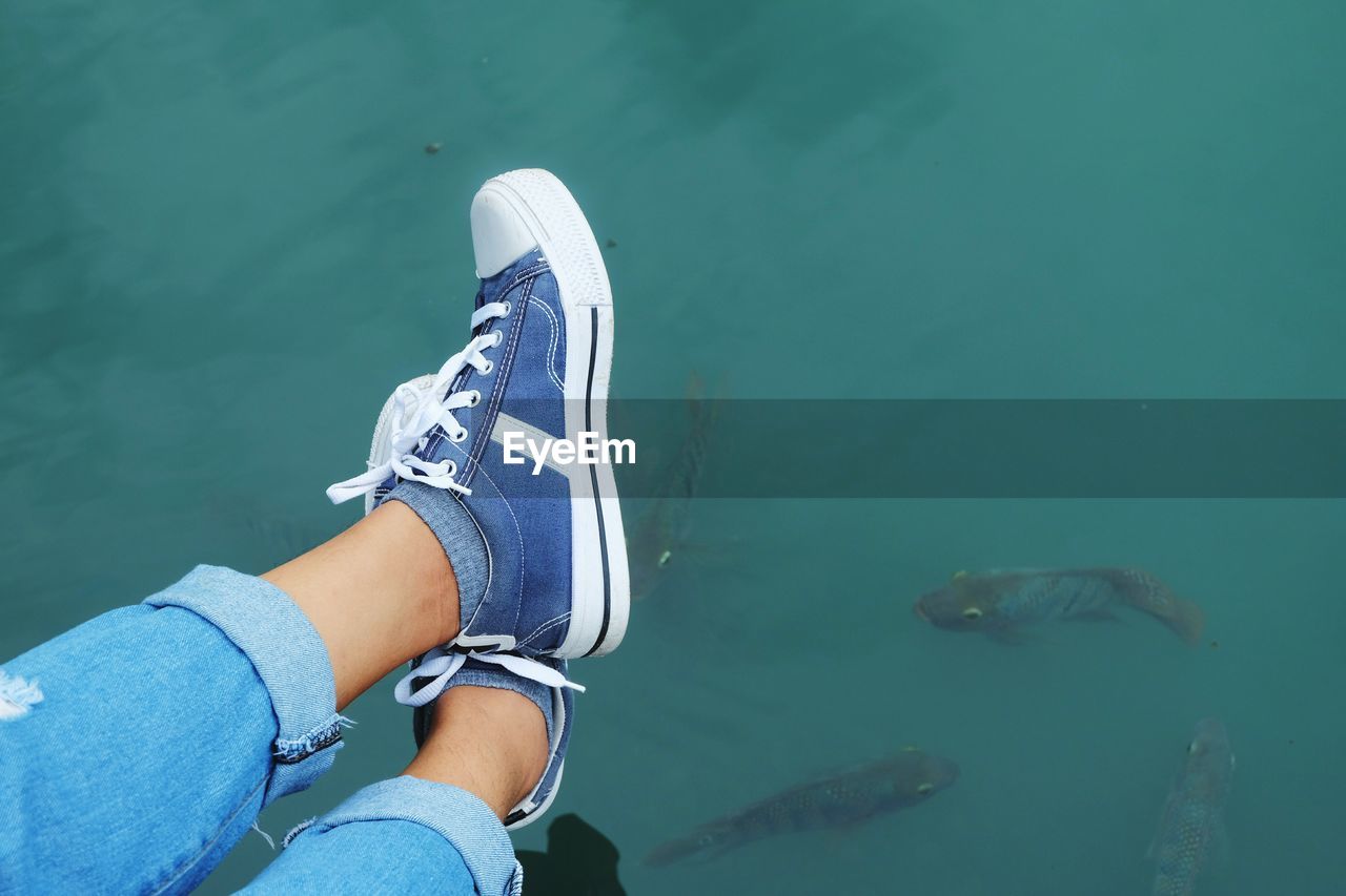 Low section of woman wearing shoes over lake