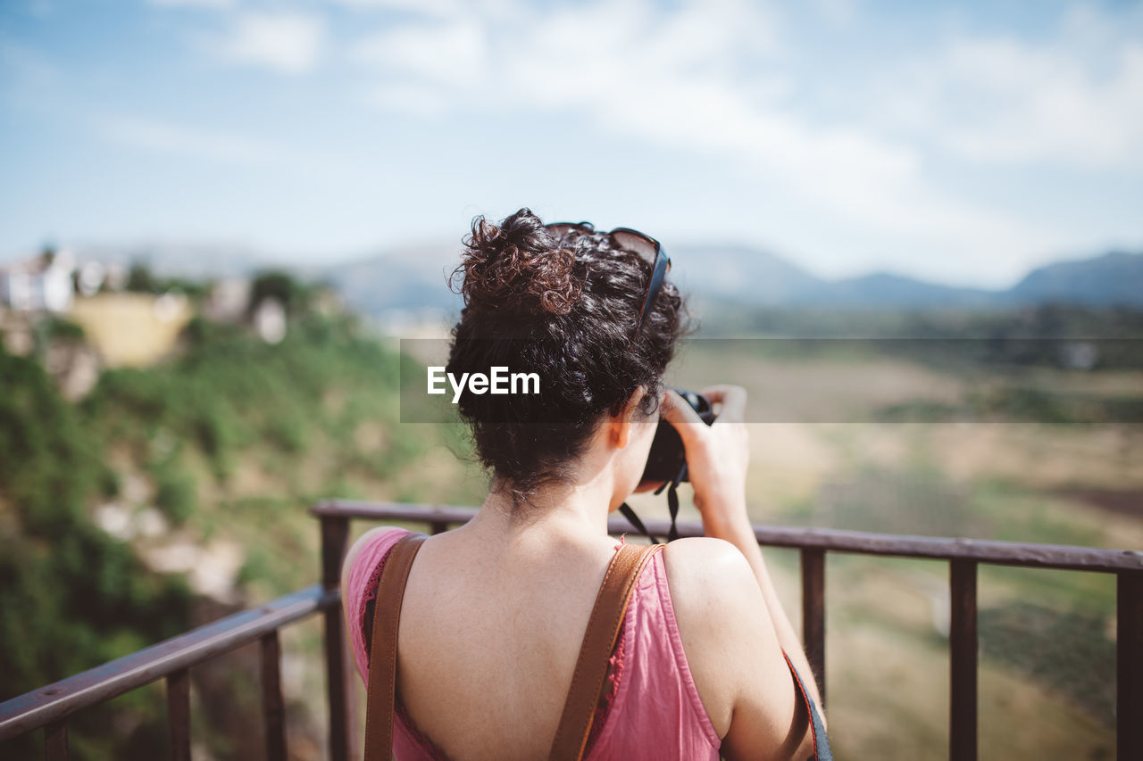 Rear view of woman photographing against sky