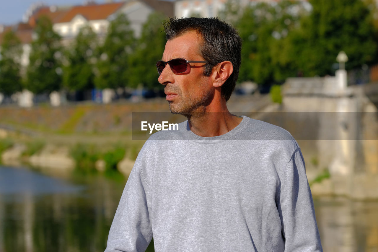 Man wearing sunglasses looking away while standing outdoors