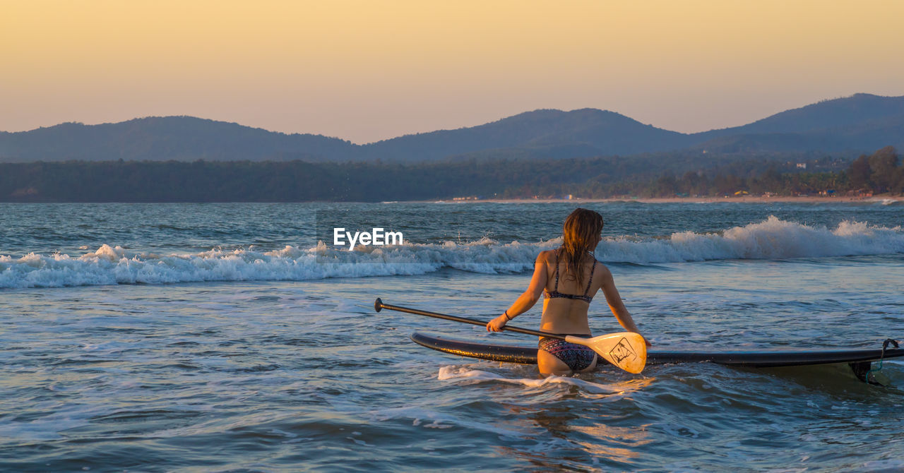 WOMAN IN BOAT ON SEA AGAINST SKY