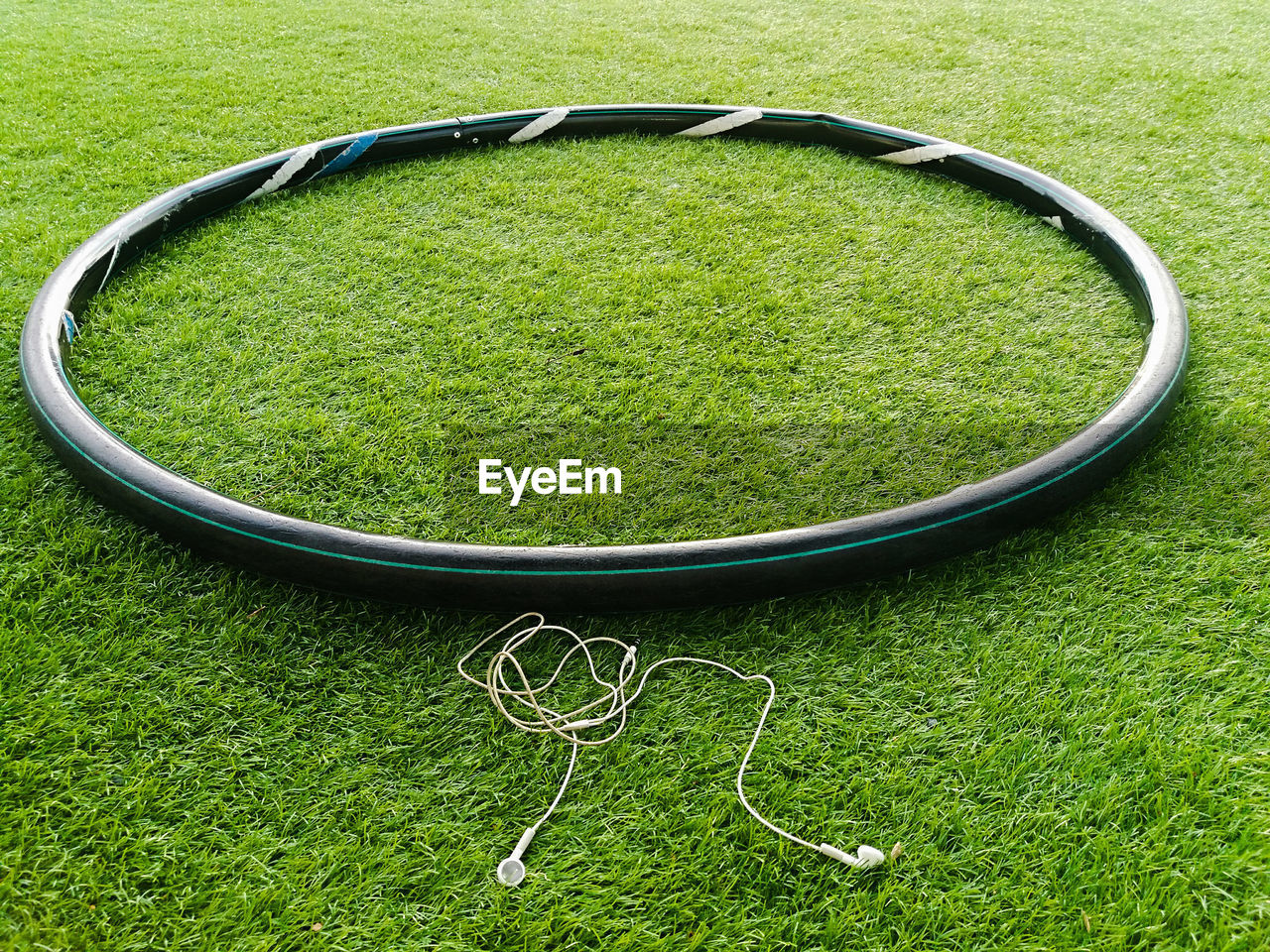 High angle view of hula hoop by in-ear headphones on grassy field