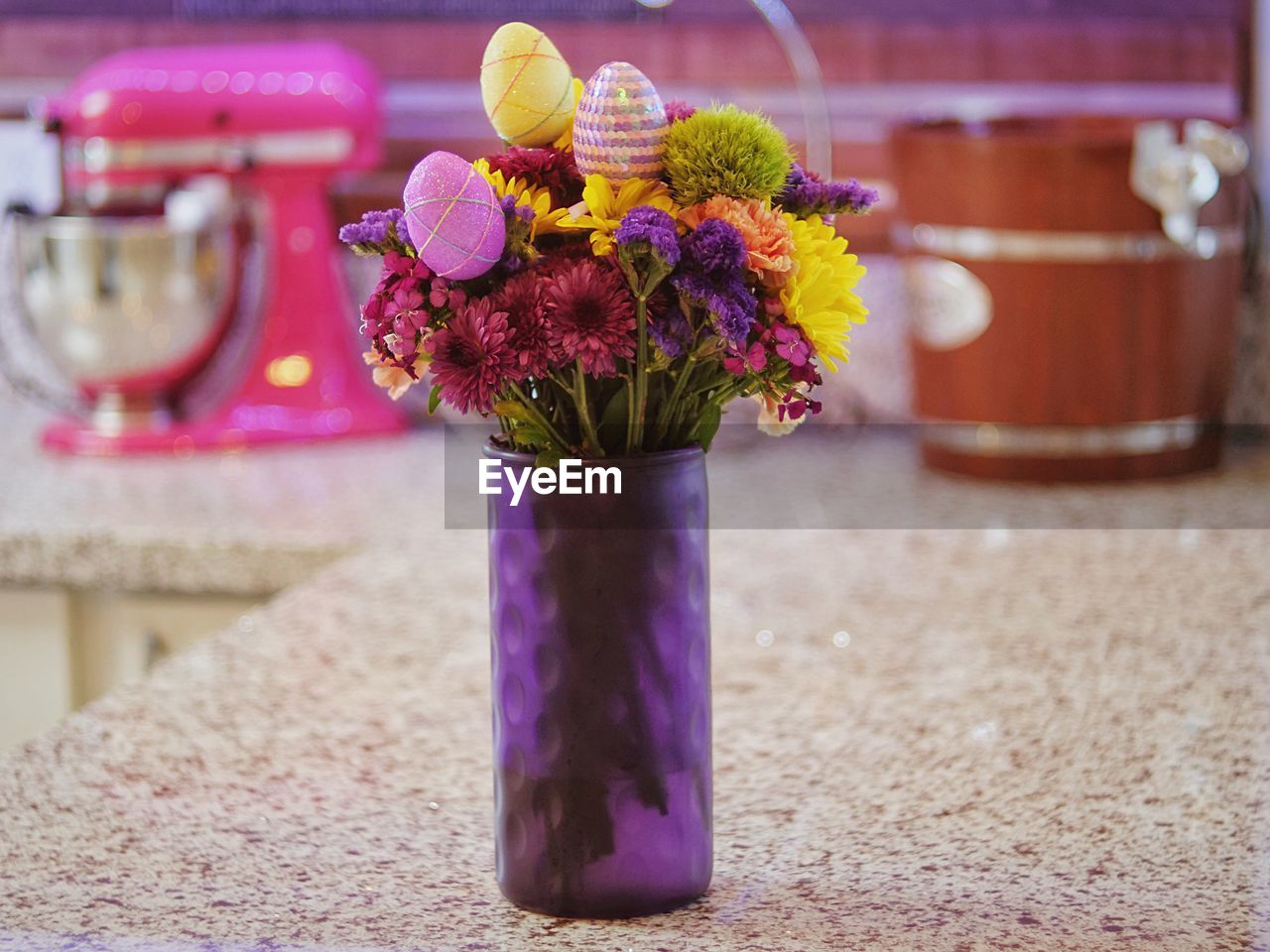 Close-up of purple flower pot on table with purple and pink artificial flowers 