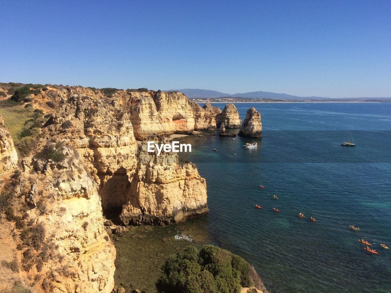 Scenic view of sea and rocks against clear blue sky