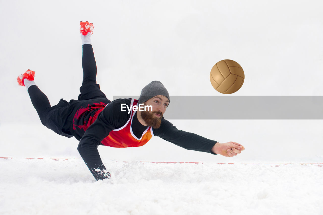 Full length of young man playing volleyball in snow