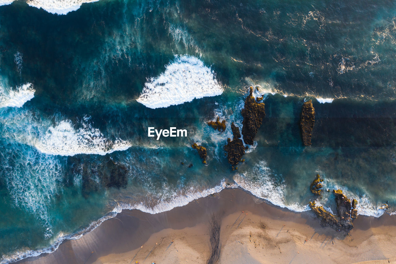 Aerial view of waves splashing on rocks at beach