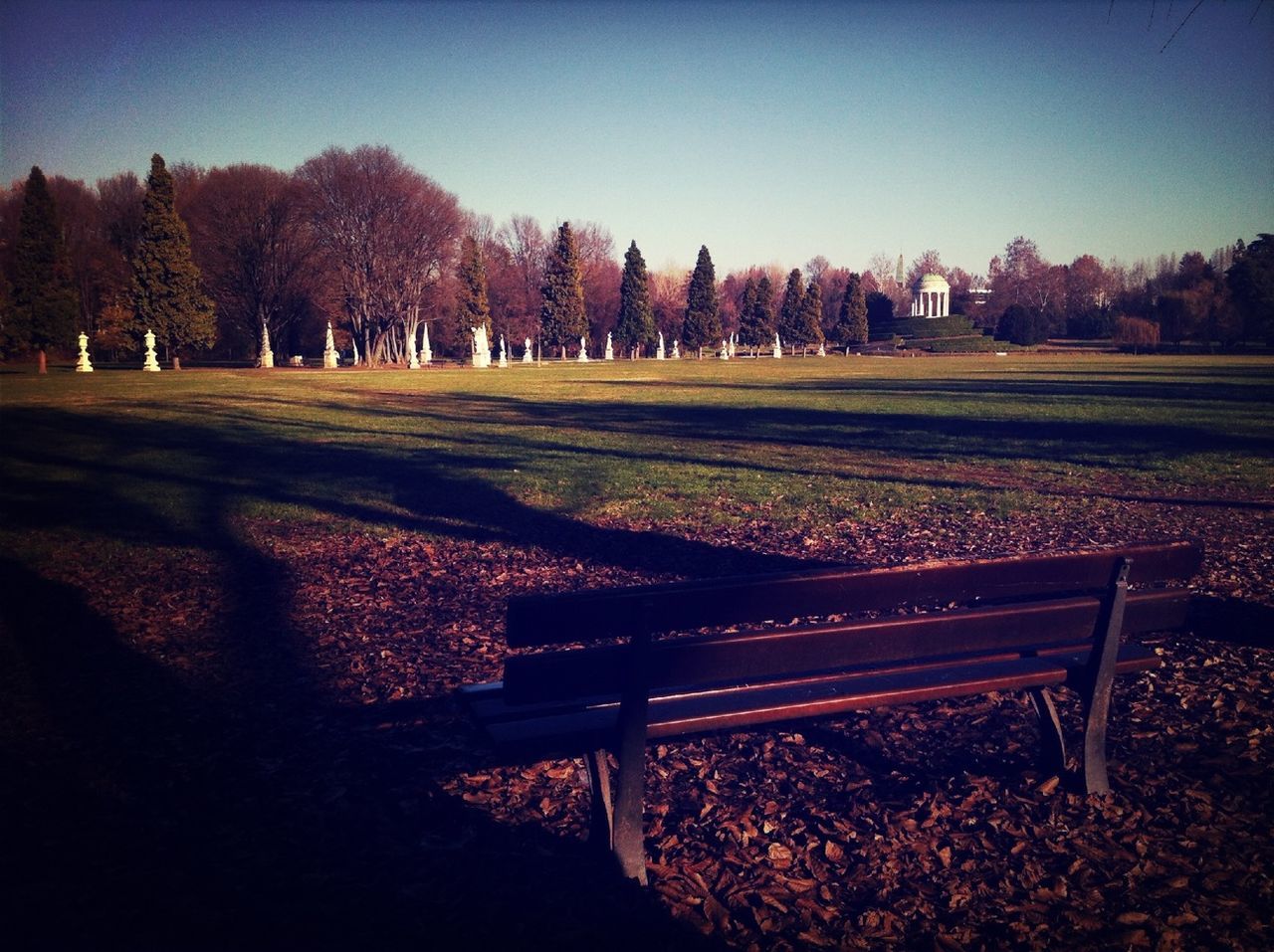 Empty bench at park against clear sky